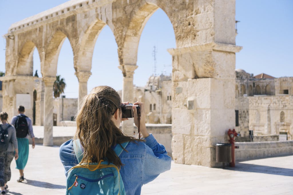 A tourist photographs the ancient stone arches in Jerusalem's Old Town, capturing the essence of travel and history.
